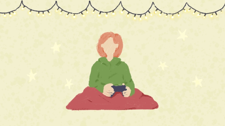 Woman holding a PS controller with a blanket thrown over her and Christmas lights above